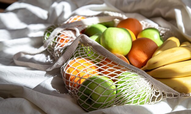 Bolsa de hilo con frutas en la cama con rayos de sol.