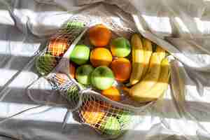 Foto gratuita bolsa de hilo con frutas en la cama con rayos de sol.