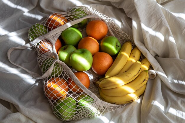 Bolsa de hilo con frutas en la cama con rayos de sol.