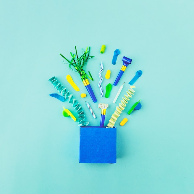 Bolsa de papel con accesorios de cumpleaños en superficie verde.