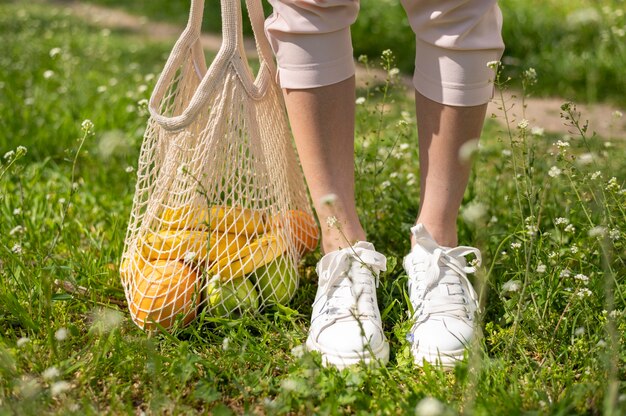 Bolsa reutilizable de primer plano cerca de pies de mujer