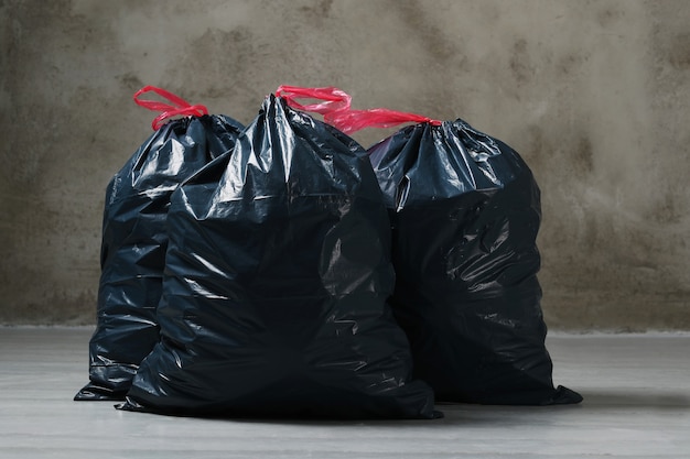 Montón de bolsas de basura negras llenas de basura cerca de la pared de  ladrillo en la calle