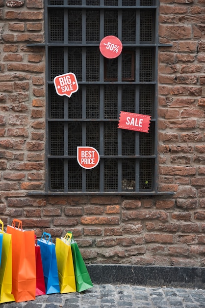 Foto gratuita bolsas de compra y venta de tabletas cerca de la ventana en la pared de ladrillo