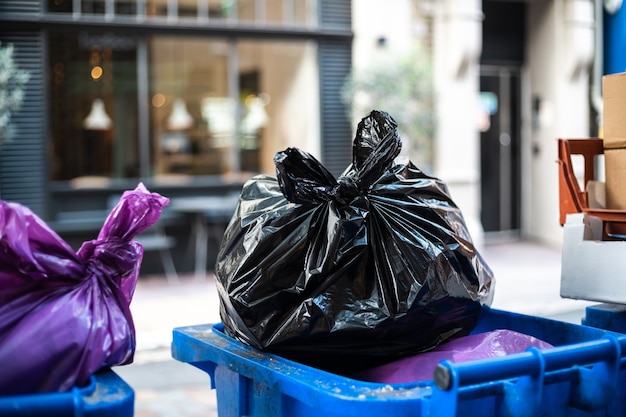 Y bolsas negras de basura en un cubo de basura durante el día