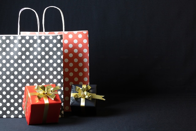 Bolsas de papel de lunares con cajas de regalo de Navidad aisladas sobre un fondo oscuro