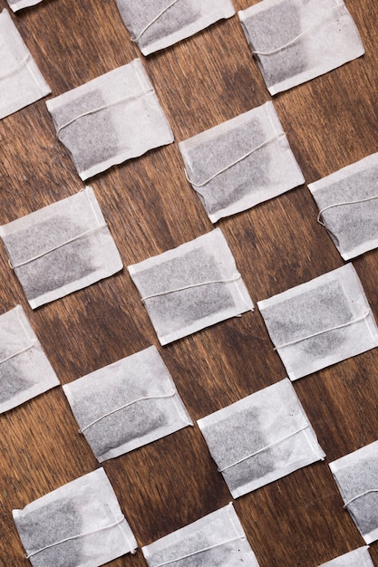 Bolsita de té blanca cruzada sobre fondo de madera con textura