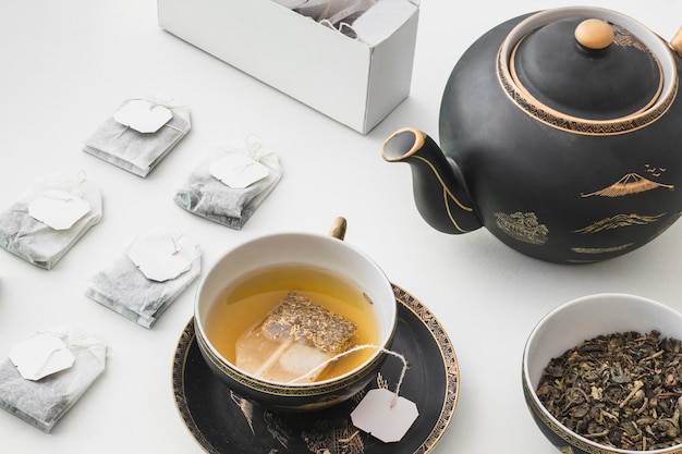 Bolsita de té herbaria en la taza en el fondo blanco