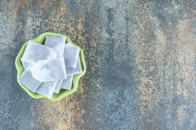 Foto gratuita bolsitas de té negro en un tazón verde sobre fondo de mármol.