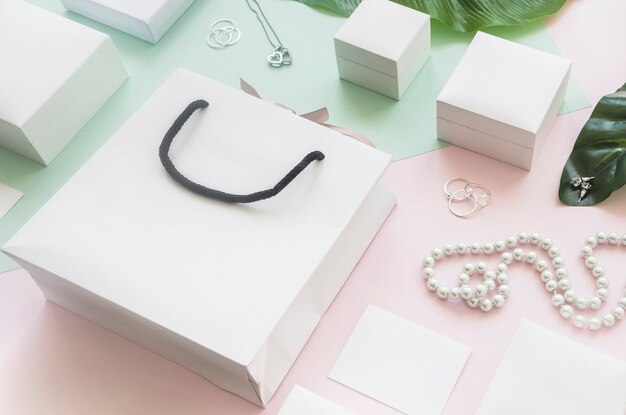 Bolso de compras blanco y cajas de regalo con joyas en colores de fondo