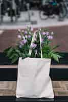 Foto gratuita bolso de mano en algodón blanco con hermosas flores moradas eustoma.