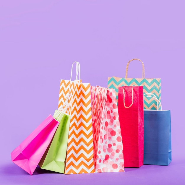 Bolsos de compras vacíos coloridos en fondo púrpura