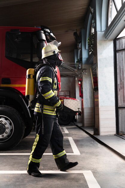 Bombero en la estación equipado con traje protector y máscara contra incendios.