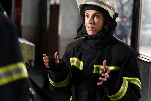 Foto gratuita bombero femenino en la estación equipada con traje y casco de seguridad