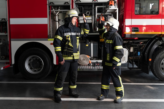 Bomberos masculinos y femeninos en la estación chocando los cinco después de la misión exitosa