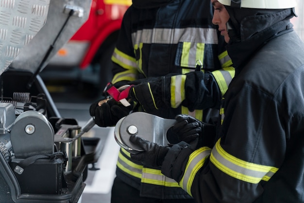 Bomberos masculinos y femeninos trabajando juntos en trajes y cascos