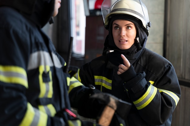 Bomberos masculinos y femeninos trabajando juntos en trajes y cascos