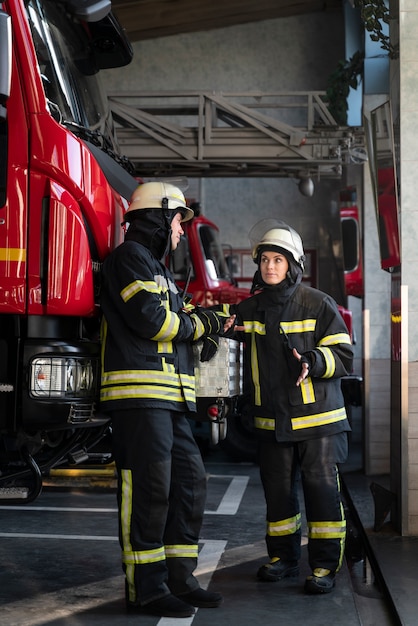 Bomberos masculinos y femeninos trabajando juntos en trajes y cascos