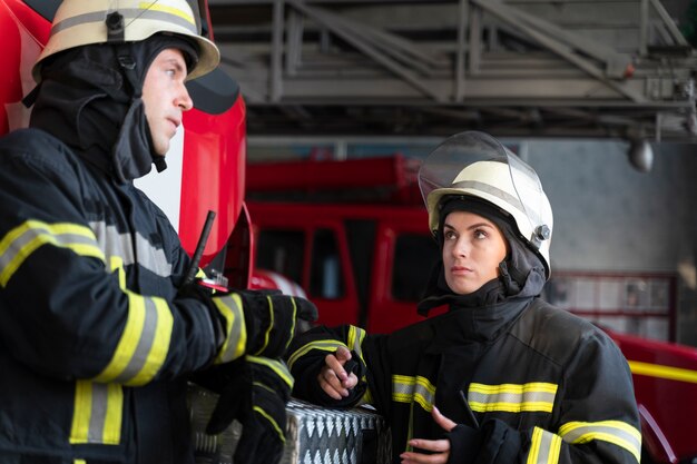 Bomberos masculinos y femeninos trabajando juntos en trajes y cascos