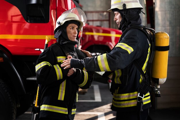 Bomberos masculinos y femeninos trabajando juntos en trajes y cascos