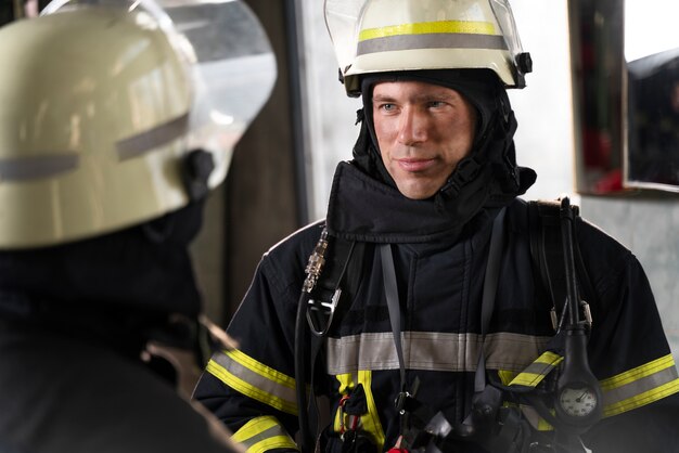 Bomberos masculinos y femeninos trabajando juntos en trajes y cascos