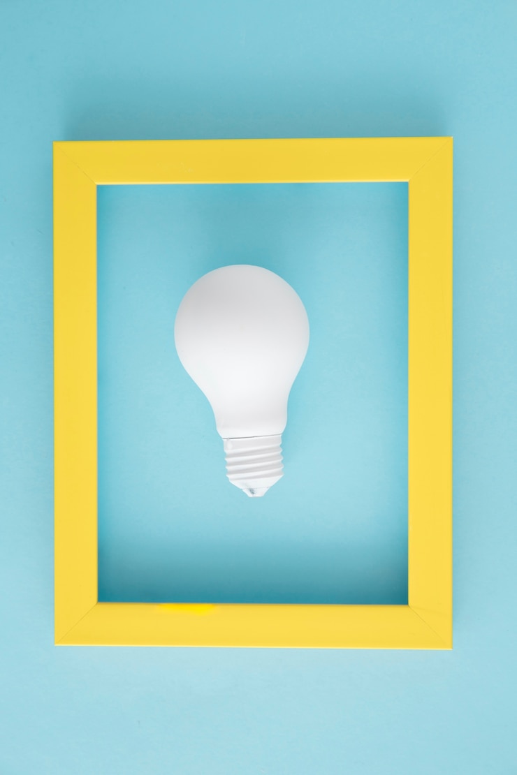 Foto gratuito bombilla de luz blanca con marco amarillo sobre fondo azul