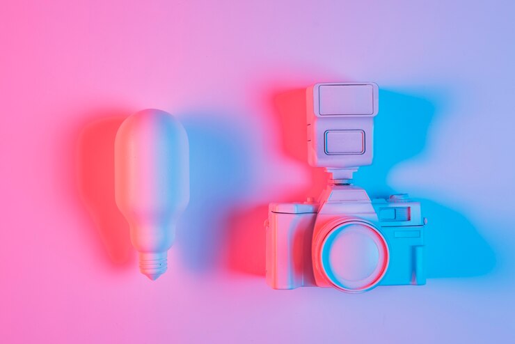 Foto gratuito bombilla de luz rosa y cámara con luz azul sobre superficie rosa
