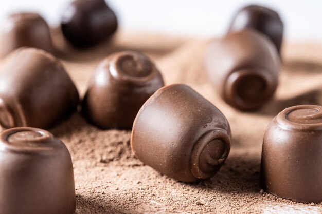 Bombones de chocolate y cacao en polvo aislado sobre fondo blanco.