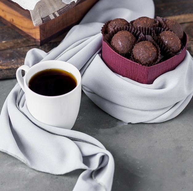 Bombones de chocolate y una taza de café blanco