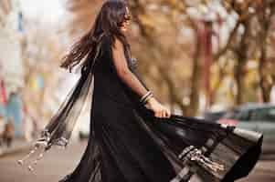 Foto gratuita bonita chica india con vestido de sari negro posó al aire libre en la calle de otoño