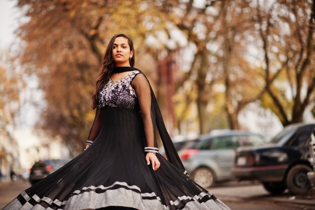 Bonita chica india con vestido de sari negro posó al aire libre en la calle de otoño