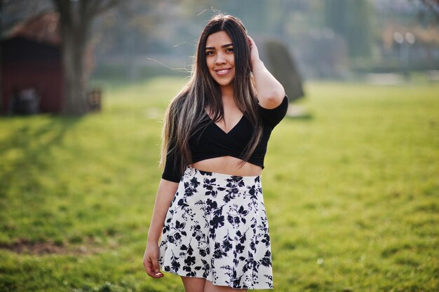 Bonita chica modelo latina de Ecuador vestida con tops negros y falda posada en la calle