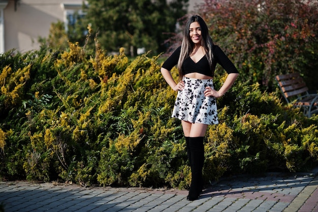 Bonita chica modelo latina de Ecuador vestida con tops negros y falda posada en la calle