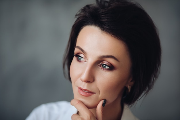 Bonita modelo de mujer caucásica con pelo corto aislado sobre fondo gris studio