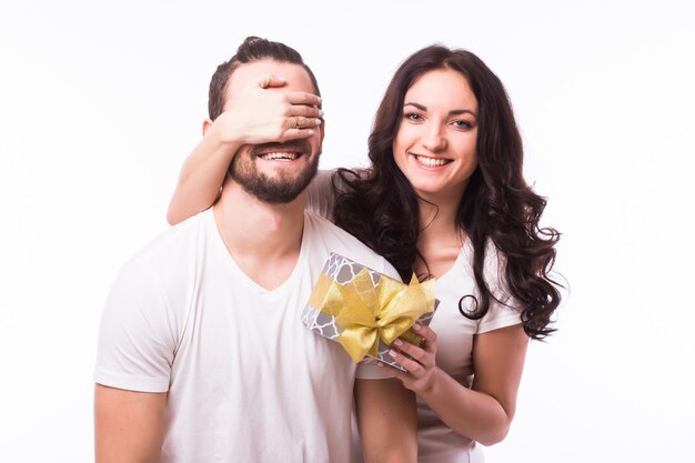 Bonita morena sorprendente novio con un regalo sobre fondo blanco.