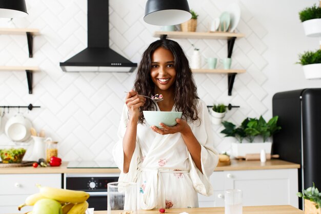 Bonita mujer africana está comiendo avena en la mañana