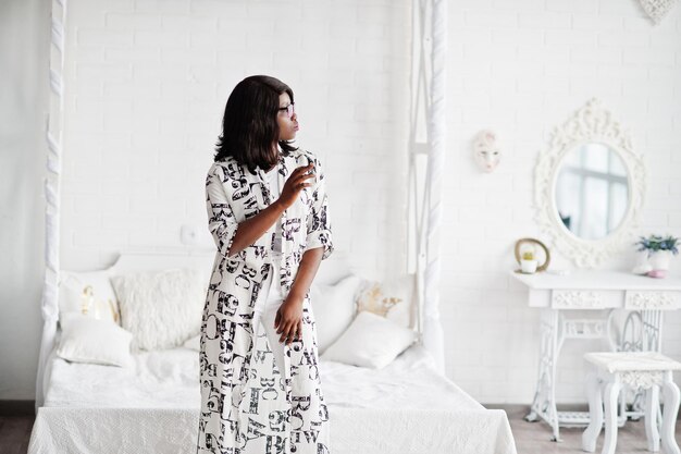 Bonita mujer afroamericana con anteojos vestido blanco y negro posado en la habitación