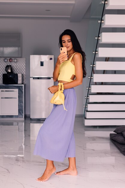 Bonita mujer blogger de moda vistiendo top amarillo y pantalón morado