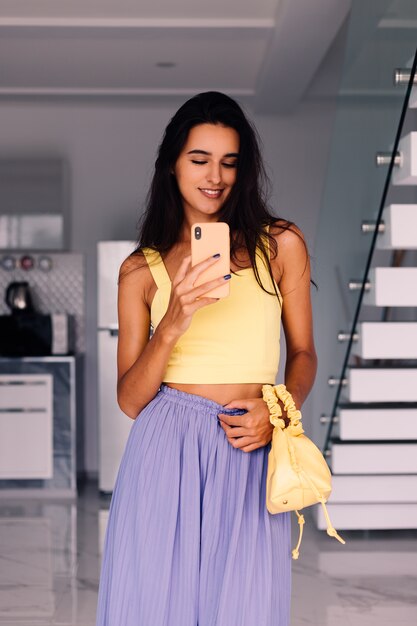 Bonita mujer blogger de moda vistiendo top amarillo y pantalón morado