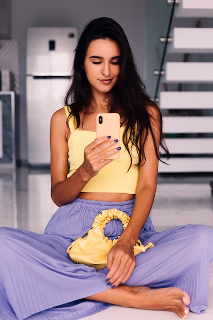 Bonita mujer blogger de moda vistiendo top amarillo y pantalón morado