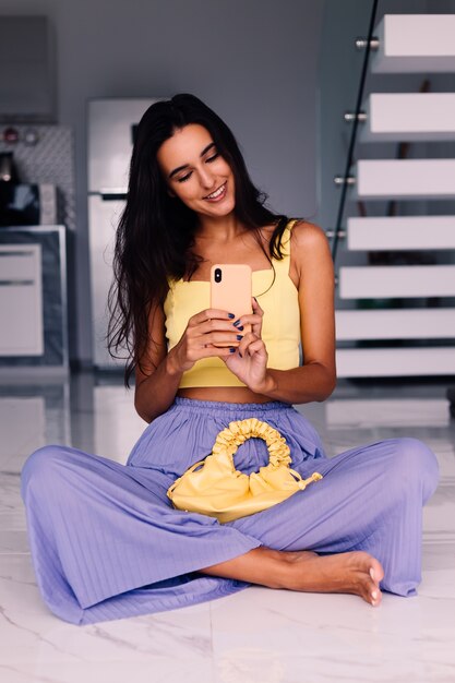 Bonita mujer blogger de moda vistiendo top amarillo y pantalón morado