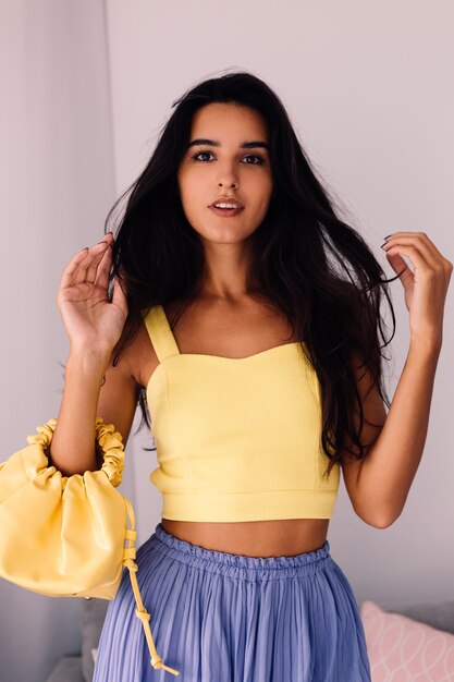 Bonita mujer blogger de moda vistiendo top amarillo y pantalón morado