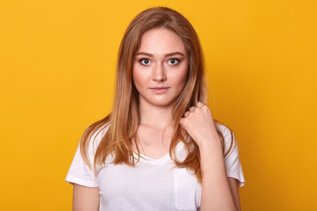 Bonita mujer con cabello rubio, vestida con camiseta blanca informal