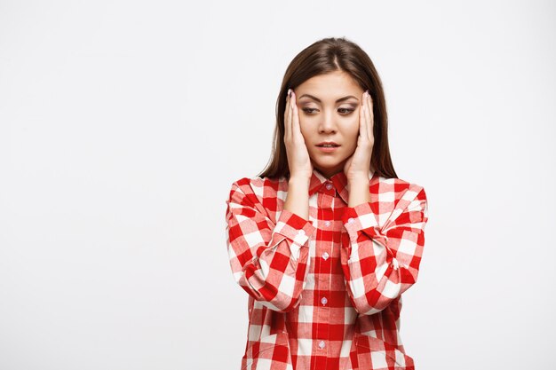 Bonita mujer en camisa roja y blanca con dolor de cabeza