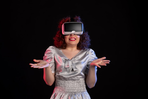 Foto gratuita bonita mujer con casco de realidad virtual en superficie oscura