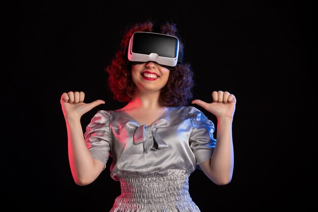 Bonita mujer con casco de realidad virtual en superficie oscura
