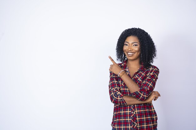 Bonita mujer negra sonriendo y apuntando al espacio de su lado