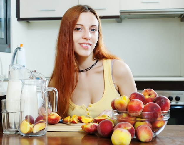 Bonita mujer de pelo largo cocina con melocotones