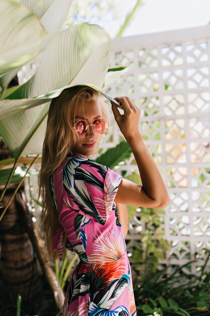 Bonita mujer de pelo largo lleva un vestido de verano mirando por encima del hombro con interés.