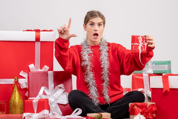 Bonita mujer sentada alrededor de regalos de Navidad en blanco