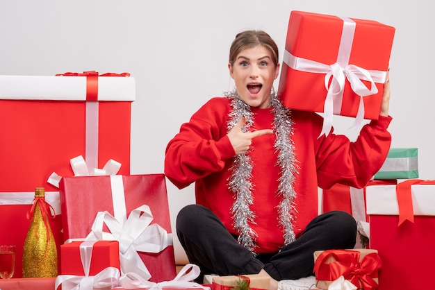 Bonita mujer sentada alrededor de regalos de Navidad en blanco